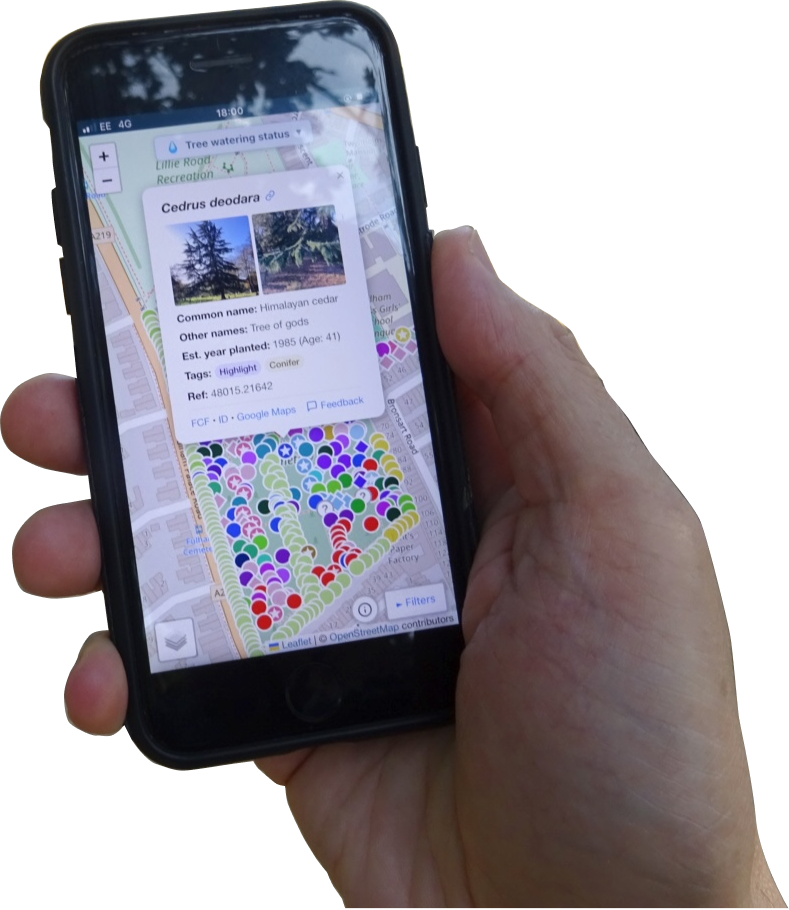 Hand holding a smartphone with the park-treemap app, in the background we can see a tranquil park